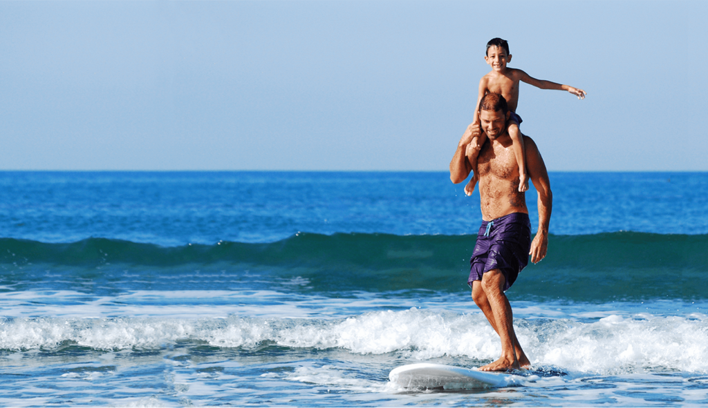 Father and son surfing together on ocean wave