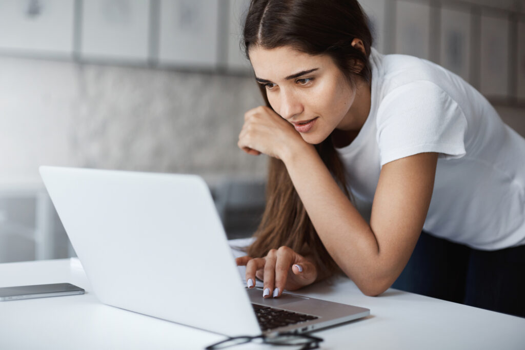 Woman working on laptop at desk in white office space